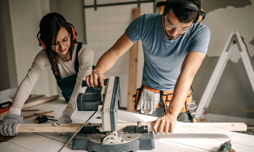 Pair of contractors cutting lumber with a chop saw